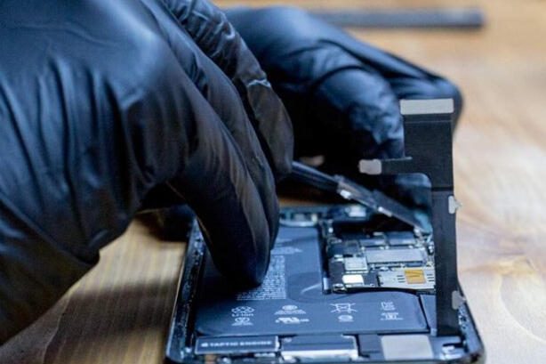 Técnico profissional reparando iPhone com ferramentas de precisão
